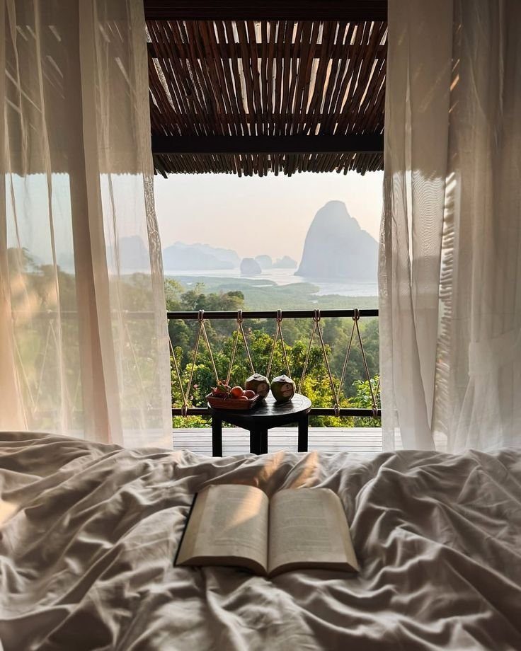Bedroom with sheer curtains opening onto limestone islands in Phang Nga Bay