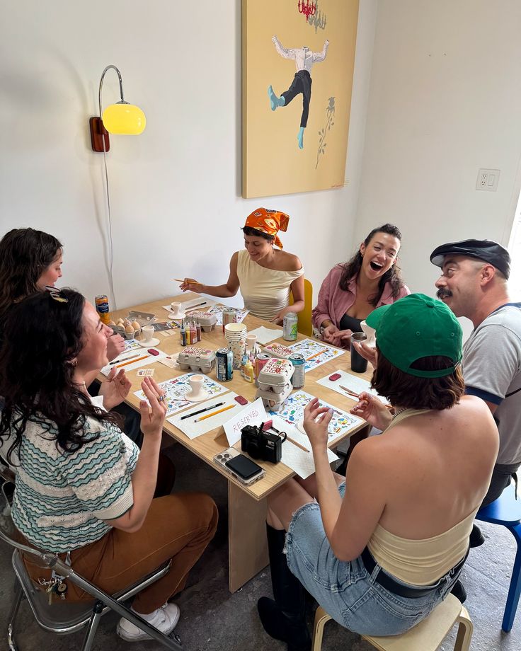 Friends laughing around a table at a hands-on craft workshop